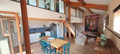a kitchen and dining room with a table and a staircase at jolie maison avec terrasse in Cessenon
