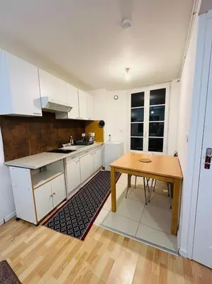 a kitchen with white cabinets and a wooden table at Appart T3 centre ville Castres in Castres