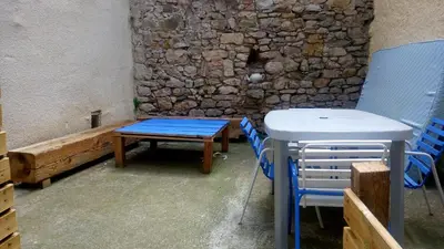 a table and chairs in a room with a stone wall at Gite rue Tranquille in Padern