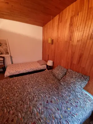 a bedroom with a bed and a wooden wall at Gite rue Tranquille in Padern