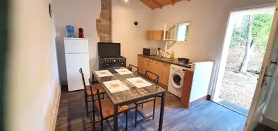a kitchen with a table and a stove and a microwave at Maison charmante à Narbonne avec piscine et jardin in Narbonne