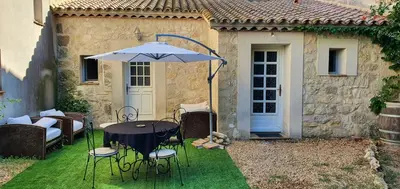 a table and chairs with an umbrella in front of a house at Maison charmante à Narbonne avec piscine et jardin in Narbonne