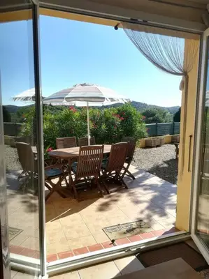 a patio with a table and chairs and an umbrella at Gîte Le Bel-Estar in Bélesta
