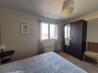 a bedroom with a large bed and a chair at Gîte Le Bel-Estar in Bélesta