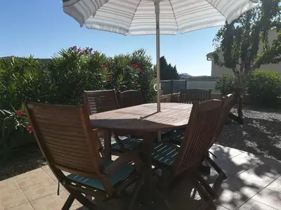 a wooden table with chairs and an umbrella at Gîte Le Bel-Estar in Bélesta