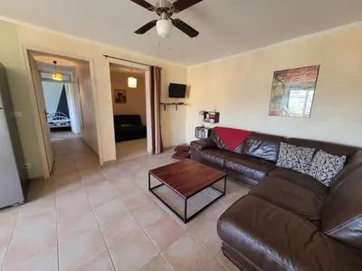 a living room with a leather couch and a table at Gîte Le Bel-Estar in Bélesta