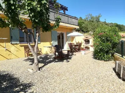 a patio with chairs and a tree in front of a house at Gîte Le Bel-Estar in Bélesta