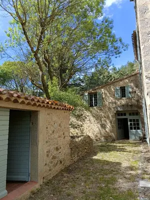 a stone house with a garage and a tree at Le Moulin de La Grave - Lagrasse in Lagrasse