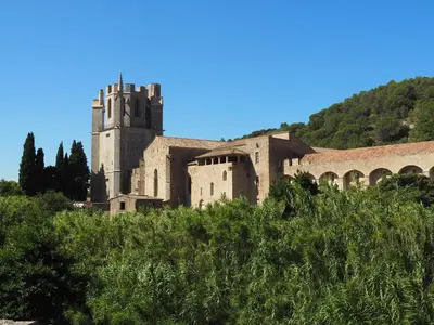 an old building with a tower on a hill at Le Moulin de La Grave - Lagrasse in Lagrasse