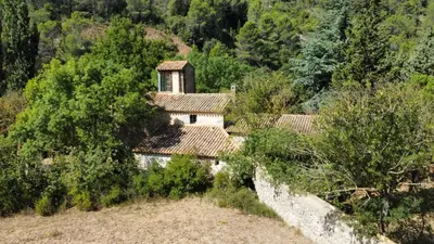 an old house on a hill with trees and bushes at Le Moulin de La Grave - Lagrasse in Lagrasse