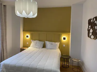 a bedroom with a large bed and a chandelier at La Feuilleraie in Montséret
