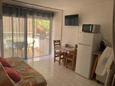 a kitchen with a refrigerator and a table with a microwave at studio cabine mer in Port-la-Nouvelle