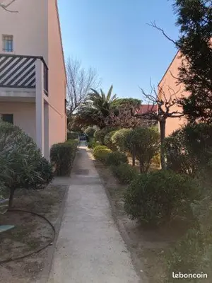 a sidewalk next to a building with bushes and trees at studio cabine mer in Port-la-Nouvelle