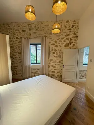 a bedroom with a large white bed and two lights at La Petite Ecurie in Montséret