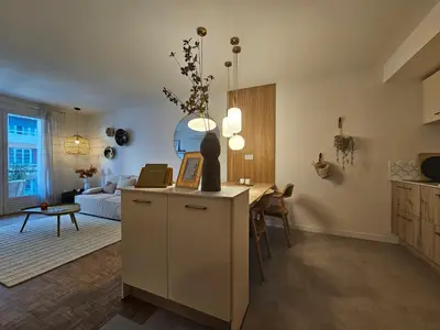 a living room with a kitchen and a living room with a couch at LE JACQUARD Appartement Type 2 proche des Halles in Narbonne