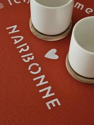 a red table with two white cups on it at LE JACQUARD Appartement Type 2 proche des Halles in Narbonne