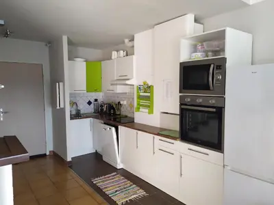 a kitchen with white cabinets and a microwave at Côté port in Gruissan