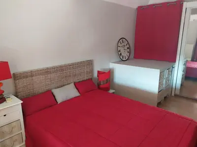 a bedroom with a red bed and a clock on the wall at Côté port in Gruissan