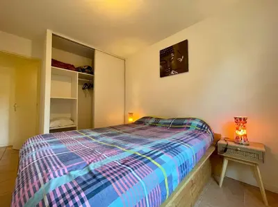 a bedroom with a bed and a table with a lamp at L'appartement Michelet - Parking privé et gratuit - 2km Cité Médiévale in Carcassonne
