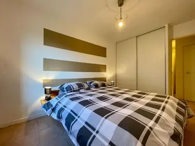 a bedroom with a bed with a black and white comforter at L'appartement Michelet - Parking privé et gratuit - 2km Cité Médiévale in Carcassonne