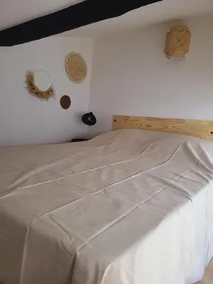 a bed in a bedroom with a white wall at Maison de village à la décoration bohème jusqu'à 6 personnes in Viviers-lès-Montagnes