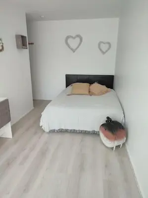 a white bedroom with a bed and a wooden floor at studio avec piscine in Gruissan
