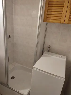 a white refrigerator in a bathroom with a shower at studio avec piscine in Gruissan