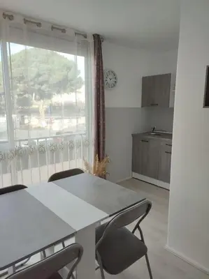 a kitchen with a table and chairs and a window at studio avec piscine in Gruissan