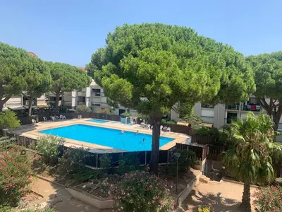 a swimming pool with a tree in front of a building at GRUISSAN PORT JOLI T3 DUPLEX in Gruissan