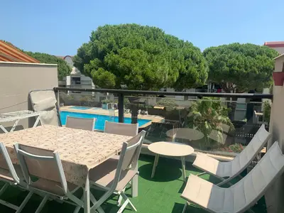 a balcony with a table and chairs and a pool at GRUISSAN PORT JOLI T3 DUPLEX in Gruissan