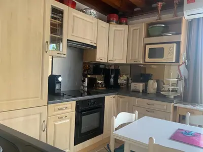 a kitchen with wooden cabinets and a table and a microwave at GRUISSAN PORT JOLI T3 DUPLEX in Gruissan