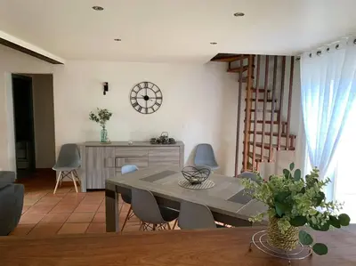 a dining room with a table and chairs and a clock at Jolie Villa piscine à 15 min du Barcarès in Salses-le-Chateau