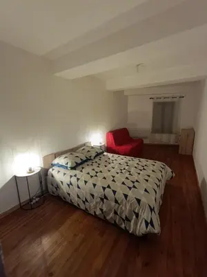 a bedroom with a bed and a red chair at La terrasse des Augustins in Limoux