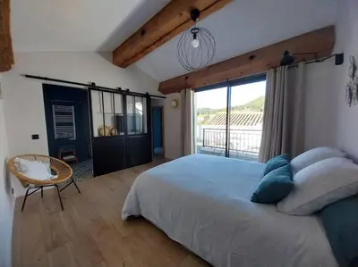 a bedroom with a large bed and a large window at La Cave... entre Narbonne et Carcassonne in Conilhac-Corbières