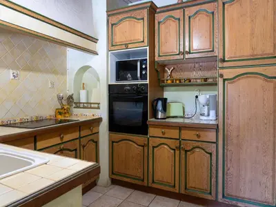 a kitchen with wooden cabinets and a stove top oven at Beautiful domaine with private pool and park in Cazouls-lès-Béziers