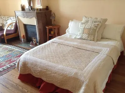a bedroom with a large bed with a fireplace at La Maison de la Riviere B&B in Espéraza