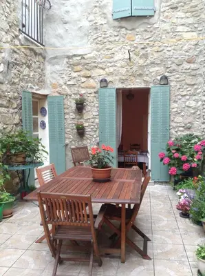 a wooden table and chairs in front of a stone building at La Maison de la Riviere B&B in Espéraza