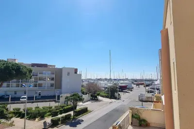 a view of a street with a building and a parking lot at Appartement Iris Résidence les Grenadines in Gruissan