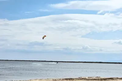 a kite flying in the sky over a body of water at Appartement Iris Résidence les Grenadines in Gruissan