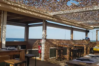 a restaurant with tables and chairs and windows at Appartement Iris Résidence les Grenadines in Gruissan