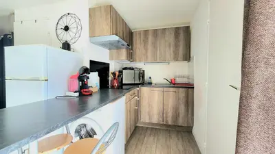 a kitchen with wooden cabinets and a white refrigerator at Appartement Iris Résidence les Grenadines in Gruissan