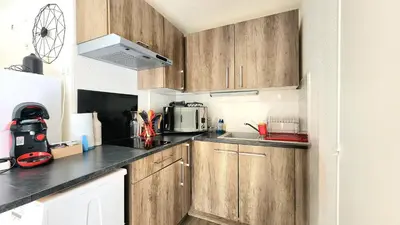 a small kitchen with wooden cabinets and a microwave at Appartement Iris Résidence les Grenadines in Gruissan