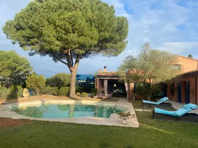 a pool in a yard with a tree and a house at L’Hacienda Francesa in Palaja