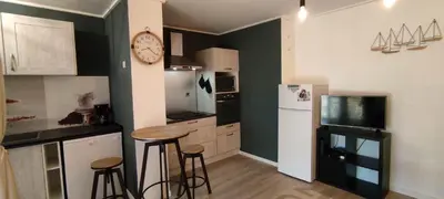 a kitchen with two stools and a clock on the wall at Appartement 4 personnes in Port-la-Nouvelle