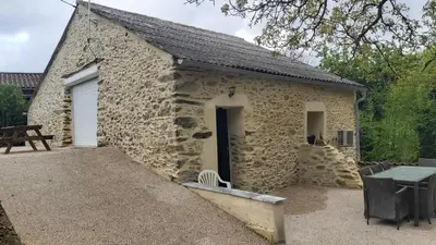 a stone building with a door and a table at La Grange du Pradel in Montredon-Labessonnié