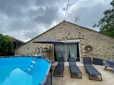 a pool with chairs and an umbrella next to a building at La Grange du Pradel in Montredon-Labessonnié