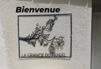 a sign on the side of a building with a tree at La Grange du Pradel in Montredon-Labessonnié
