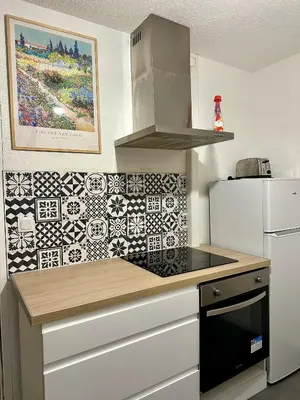 a kitchen with a stove top oven next to a refrigerator at Maison confortable - 5min de Carcassonne in Conques-sur-Orbiel