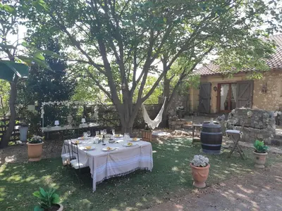 a table with a white table cloth under a tree at Chez Géraldine in Montels