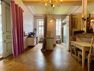 a living room with a wooden floor and pink curtains at Côté Cité appartements - Parking privé - 100m Cité médiévale in Carcassonne